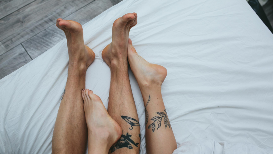 sexually transmitted diseases, legs of man and woman, both have a tattoo on one leg